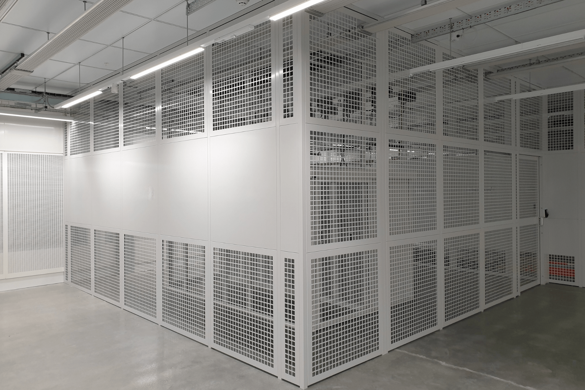 Interior view of a secure, modern data center aisle with enclosed white server cabinets and overhead cable trays.